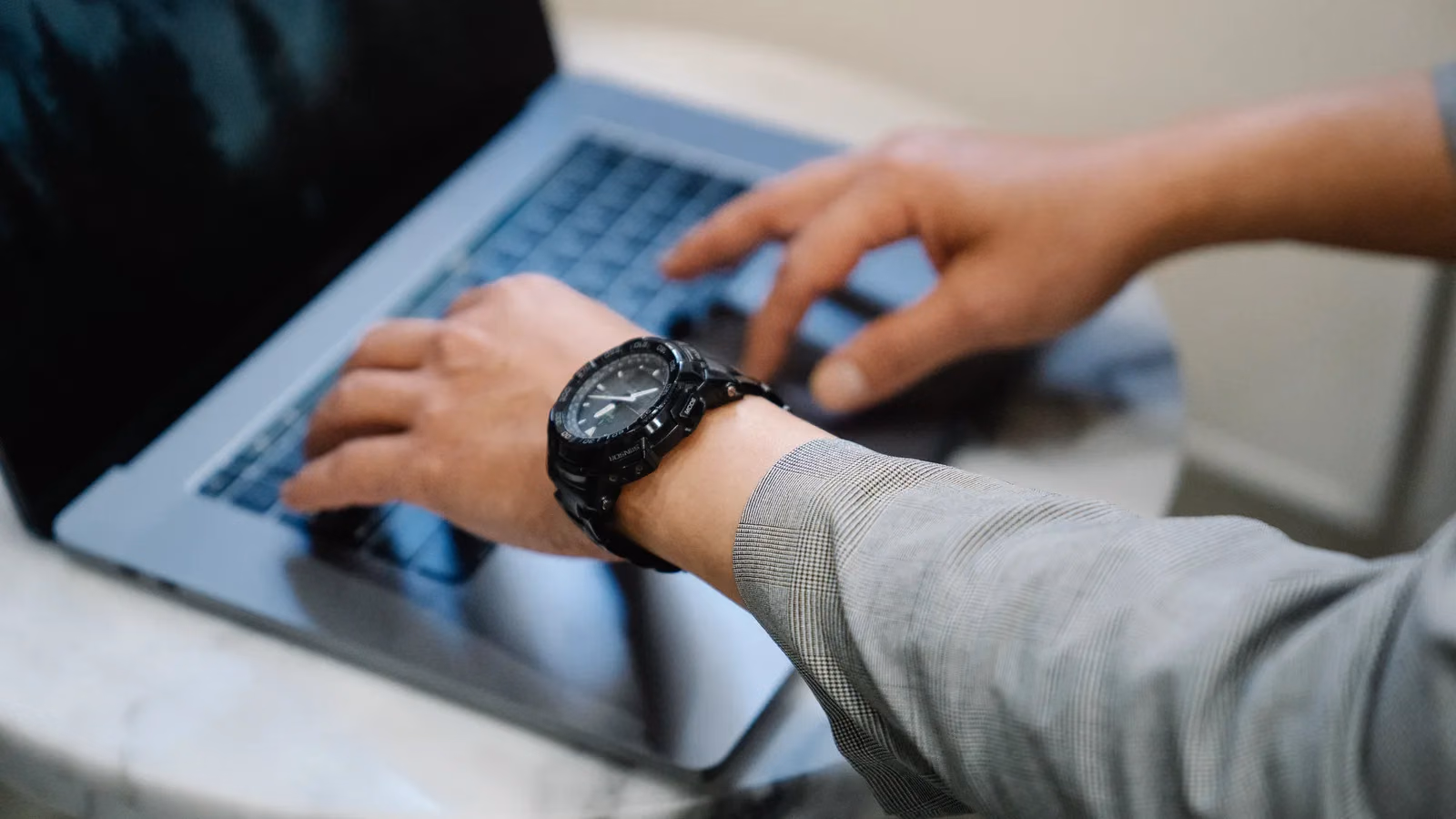 Hände tippen auf der Tastatur eines Laptops am Schreibtisch